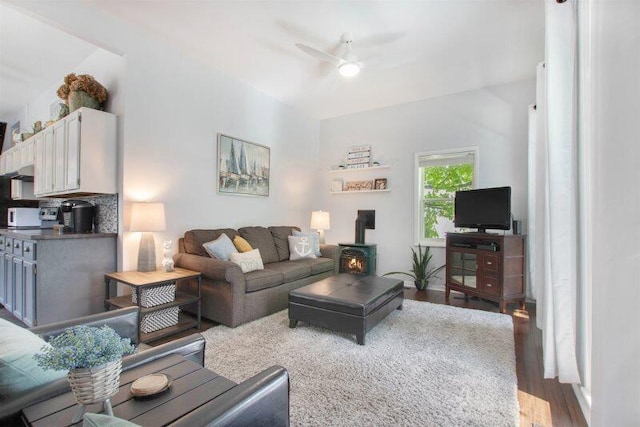 living room with hardwood / wood-style flooring, ceiling fan, and a wood stove