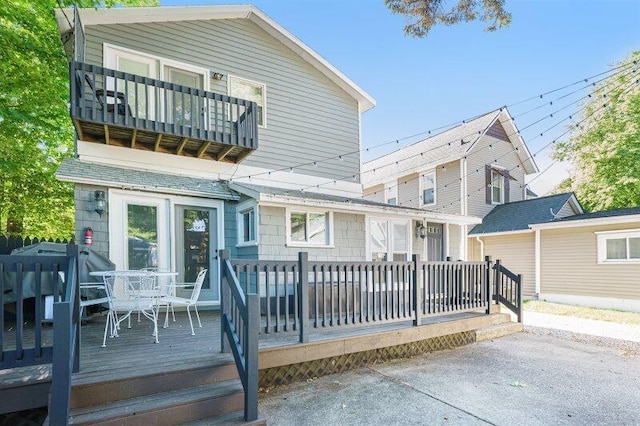 back of house with a wooden deck and a balcony