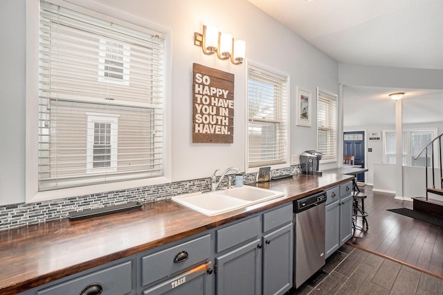 kitchen featuring stainless steel dishwasher, gray cabinets, sink, and butcher block countertops