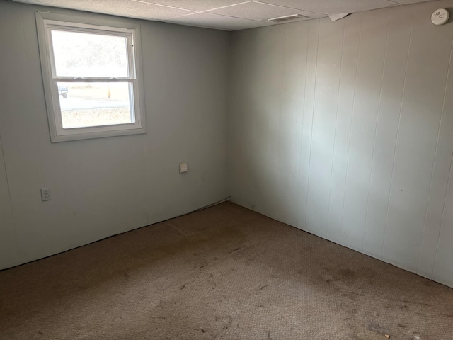 unfurnished room with carpet floors and a drop ceiling