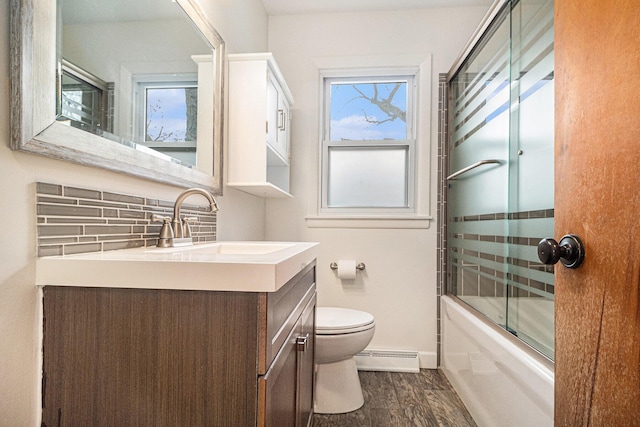 full bathroom with bath / shower combo with glass door, hardwood / wood-style flooring, vanity, a baseboard heating unit, and toilet