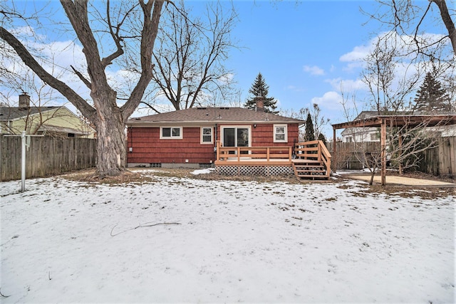 snow covered rear of property with a deck