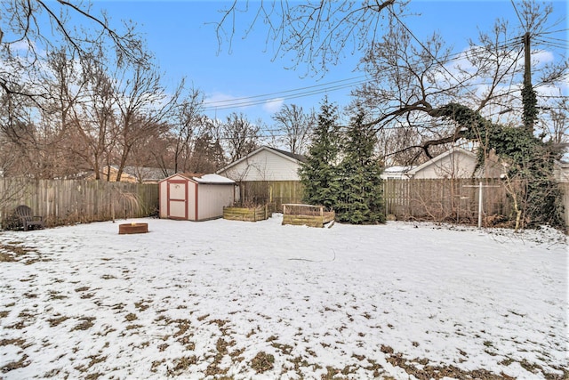 yard layered in snow featuring an outdoor fire pit and a storage shed