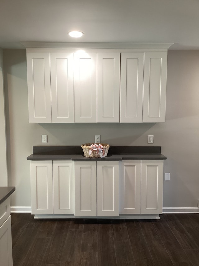 bar with white cabinetry and dark hardwood / wood-style floors