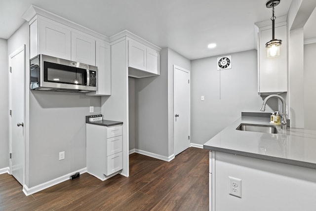 kitchen with dark hardwood / wood-style flooring, sink, decorative light fixtures, and white cabinets