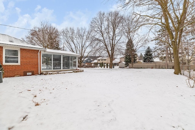 yard covered in snow with central AC and a sunroom