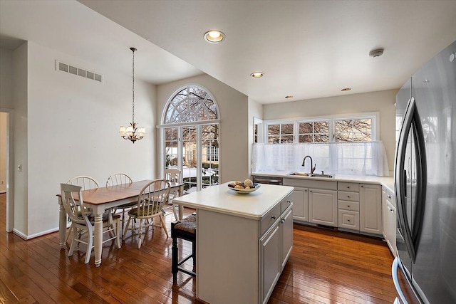 kitchen with a kitchen island, pendant lighting, stainless steel refrigerator, white cabinets, and dark hardwood / wood-style flooring