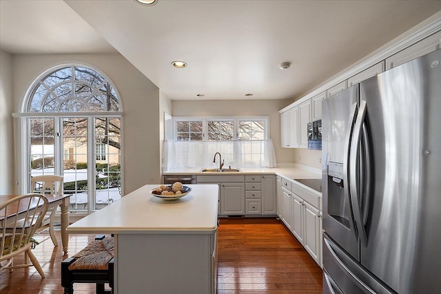 kitchen with sink, appliances with stainless steel finishes, white cabinetry, a kitchen island, and dark hardwood / wood-style flooring