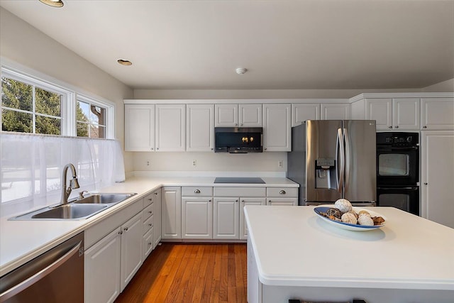 kitchen featuring sink, white cabinets, light wood-type flooring, and black appliances