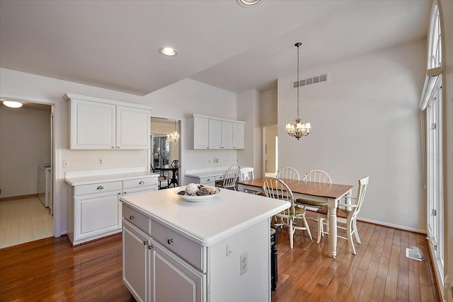 kitchen with pendant lighting, a notable chandelier, white cabinets, a kitchen island, and separate washer and dryer