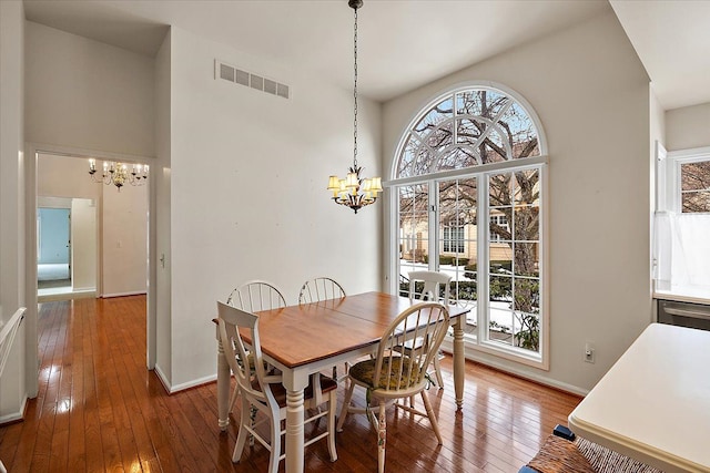 dining room featuring an inviting chandelier, wood-type flooring, and a high ceiling