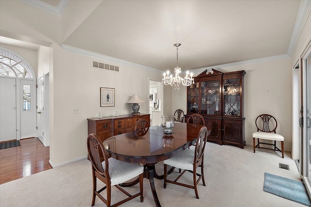 dining room with crown molding, light colored carpet, and an inviting chandelier