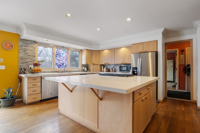 kitchen featuring ornamental molding, appliances with stainless steel finishes, a center island, and light hardwood / wood-style floors