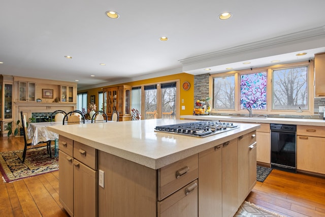 kitchen with crown molding, light wood-type flooring, stainless steel gas stovetop, and a kitchen island