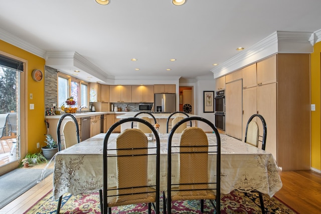 dining room with crown molding and light hardwood / wood-style floors