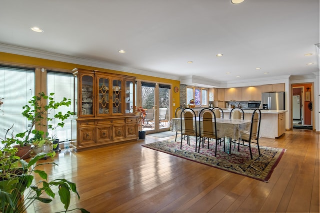 dining room with french doors, ornamental molding, and light hardwood / wood-style flooring