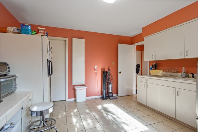 kitchen featuring light tile patterned floors, white fridge with ice dispenser, sink, and white cabinets