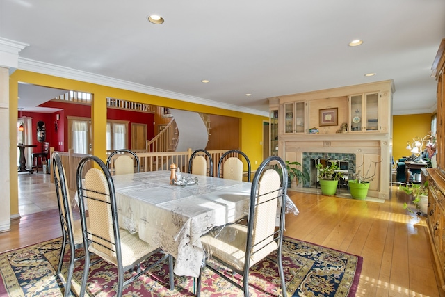 dining space featuring crown molding, a fireplace, and light hardwood / wood-style floors