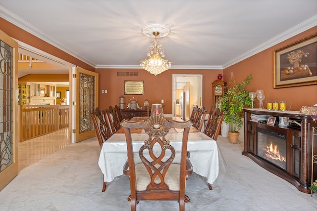 carpeted dining area featuring ornamental molding and a chandelier