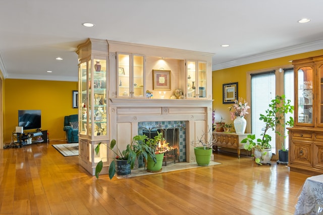 living room featuring crown molding, a fireplace, and hardwood / wood-style flooring