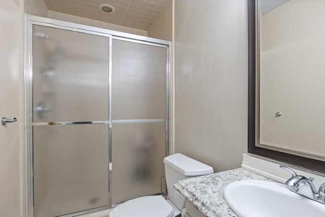 bathroom featuring a shower with door, vanity, and toilet