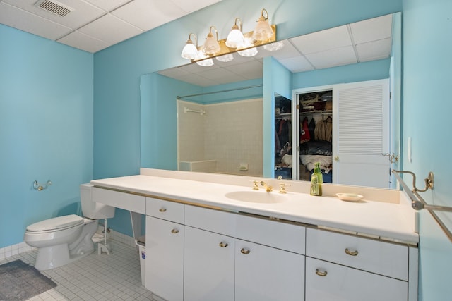 bathroom with tile patterned floors, toilet, vanity, and a drop ceiling