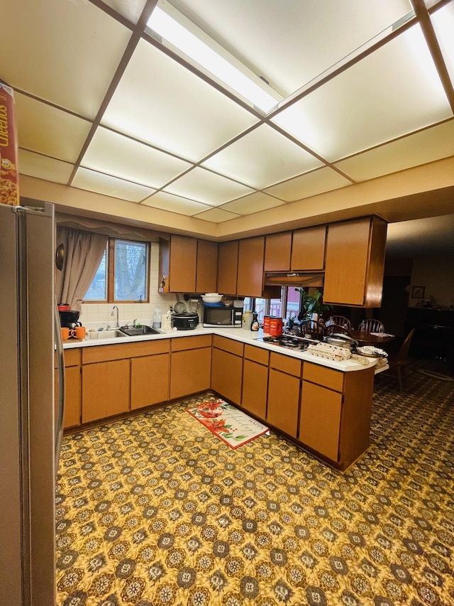 kitchen featuring sink, a paneled ceiling, and stainless steel fridge