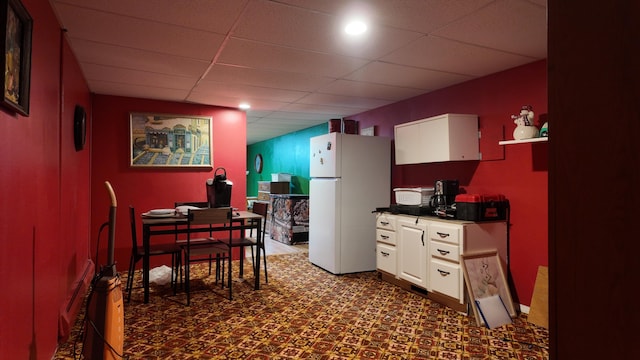 kitchen featuring a drop ceiling, white cabinets, and white fridge