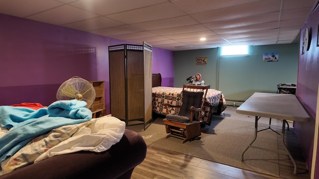 bedroom with a baseboard radiator, a paneled ceiling, and light wood-type flooring