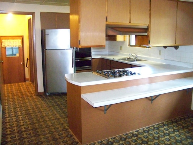 kitchen featuring light countertops, appliances with stainless steel finishes, a peninsula, and a sink