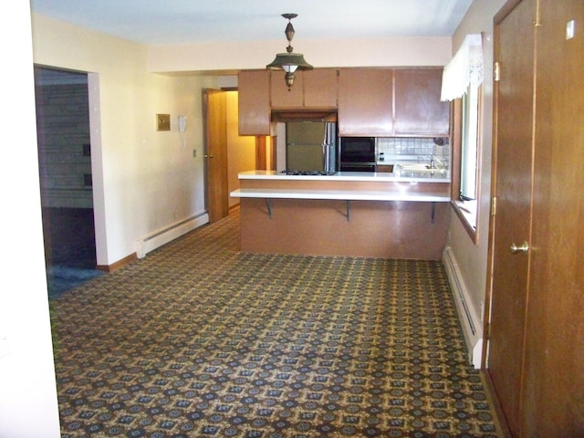 kitchen featuring brown cabinets, a breakfast bar area, a baseboard radiator, light countertops, and a peninsula