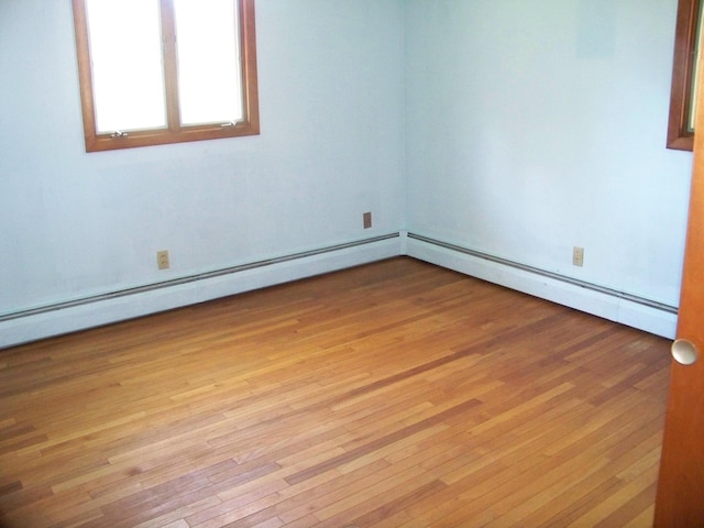 empty room with light wood-type flooring and a baseboard radiator