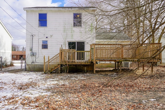 snow covered back of property with a deck