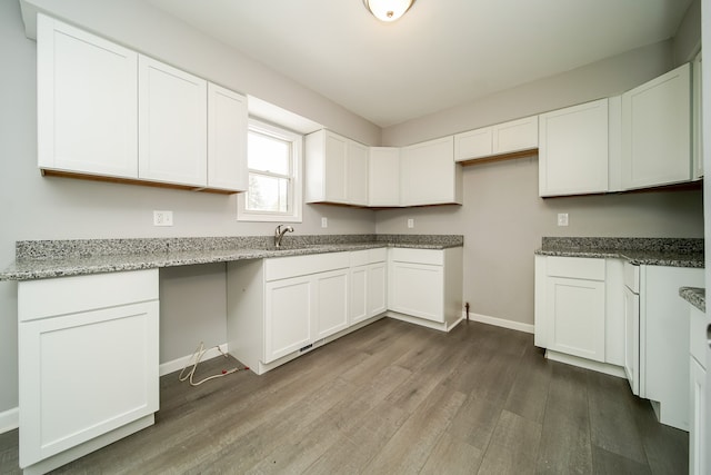 kitchen with white cabinetry, light stone countertops, and dark wood-type flooring