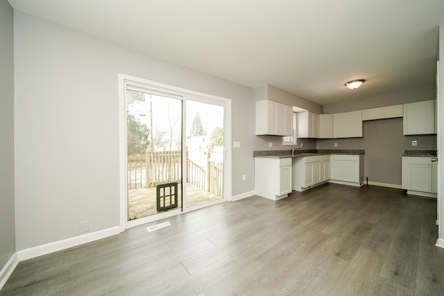 kitchen featuring dark stone countertops, sink, hardwood / wood-style floors, and white cabinets