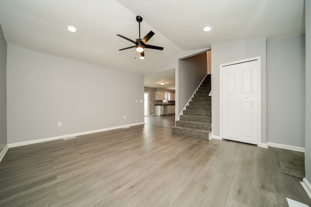 unfurnished living room featuring hardwood / wood-style flooring, vaulted ceiling, and ceiling fan