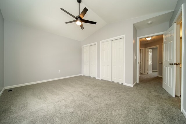 unfurnished bedroom featuring lofted ceiling, two closets, carpet, and ceiling fan