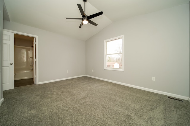 unfurnished bedroom with dark carpet, vaulted ceiling, ceiling fan, and ensuite bathroom