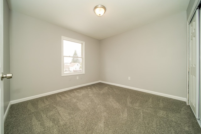 spare room with dark colored carpet