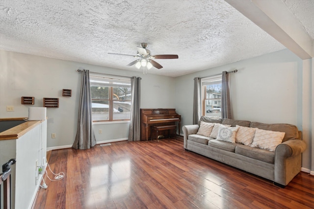 living room featuring a textured ceiling, dark wood-type flooring, and a healthy amount of sunlight