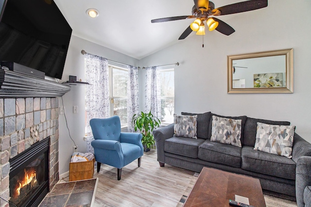 living room with a fireplace, vaulted ceiling, light hardwood / wood-style floors, and ceiling fan