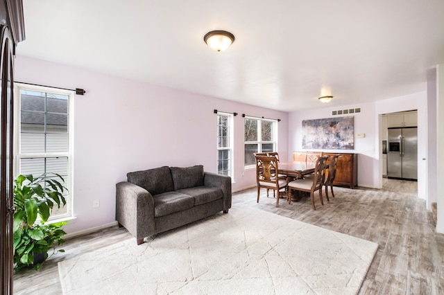 living area featuring baseboards, visible vents, and light wood-type flooring