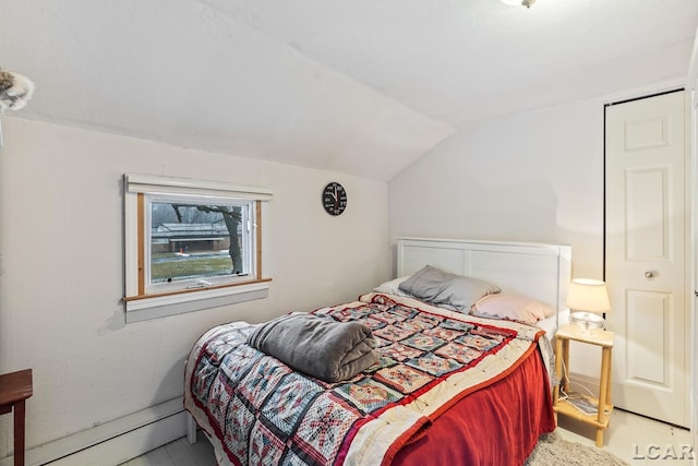 bedroom with lofted ceiling and a baseboard heating unit