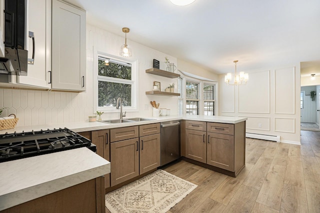 kitchen featuring sink, stainless steel dishwasher, baseboard heating, and decorative light fixtures