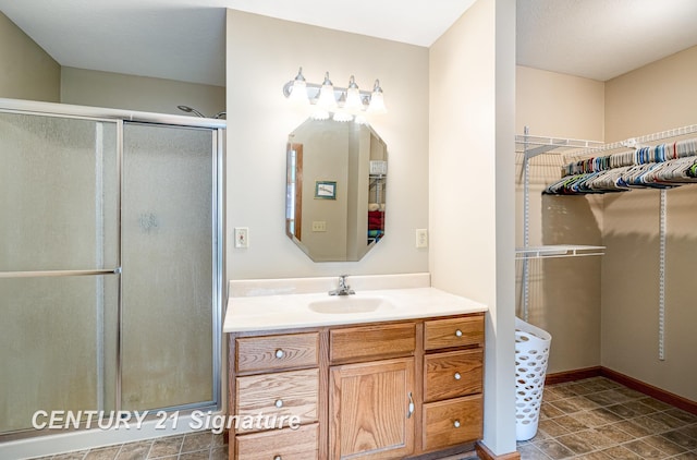 full bath with a shower stall, vanity, and baseboards