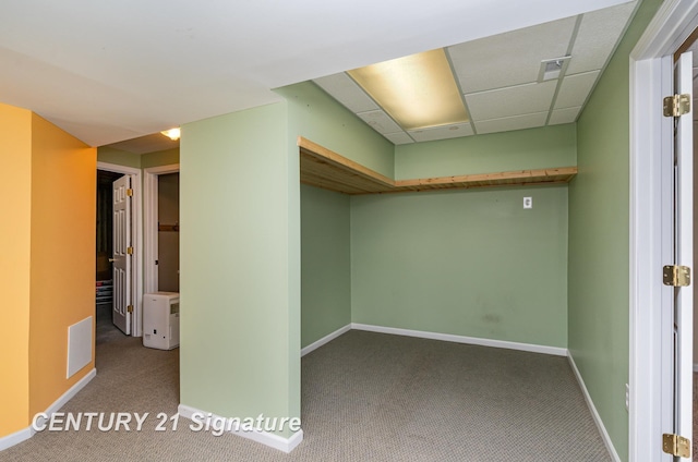 below grade area with a paneled ceiling, carpet, visible vents, and baseboards