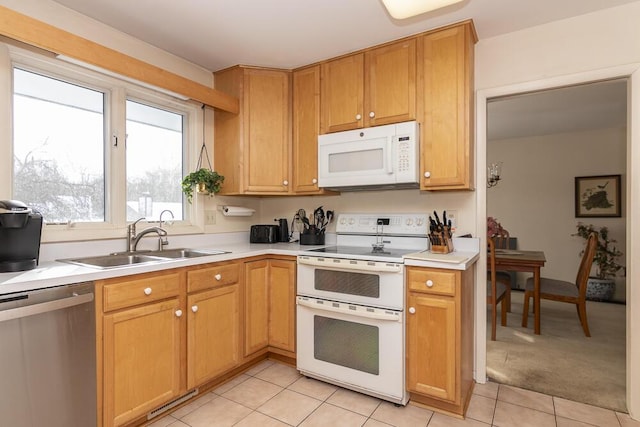 kitchen with light tile patterned flooring, stainless steel dishwasher, sink, and range with two ovens