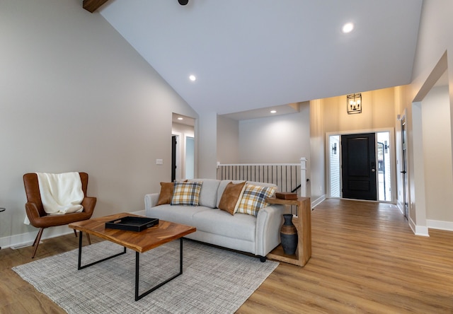 living room with beamed ceiling, high vaulted ceiling, and light hardwood / wood-style flooring