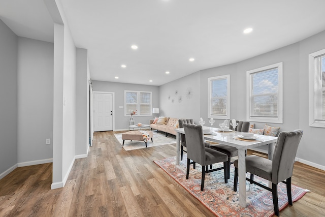 dining room with a barn door, a healthy amount of sunlight, and light wood-type flooring