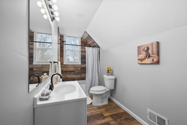 full bathroom with shower / tub combo with curtain, hardwood / wood-style floors, vanity, vaulted ceiling, and toilet